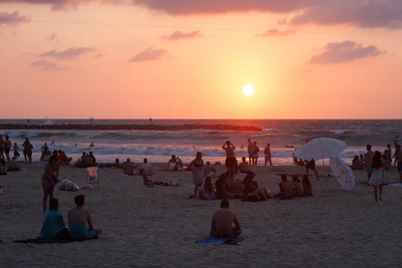 a group of people sitting on top of a sandy beach